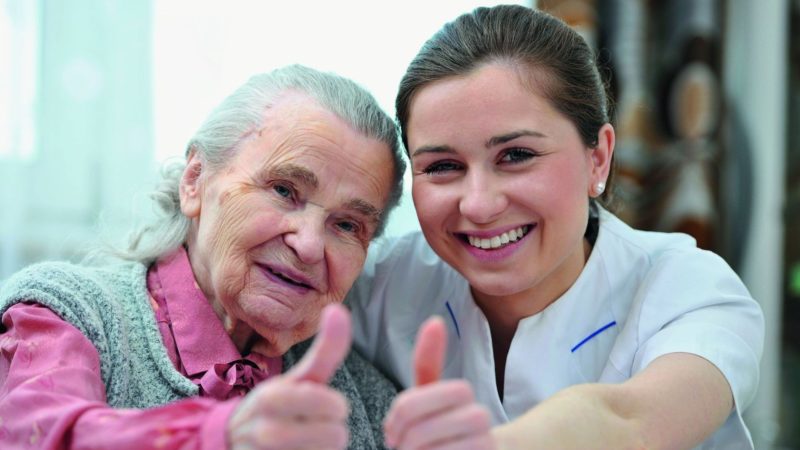Pflegedienstleitung und Seniorin blicken zufrieden in die Zukunft.