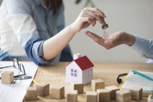 Immobilie kaufen Bremen: Schlüsselübergabe über einem Holzhausmodell auf dem Schreibtisch