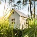 Immobilie kaufen Bremen: Holzmodell eines Hauses auf einer grünen Wiese