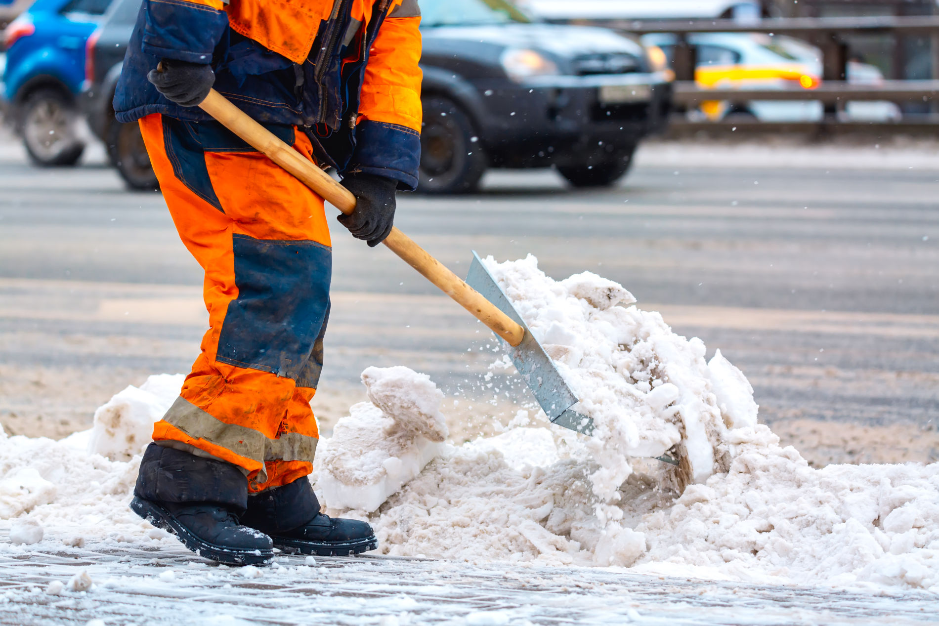 Ein Arbeiter der Gehwegreinigung Bremen schippt Schnee vom Gehweg