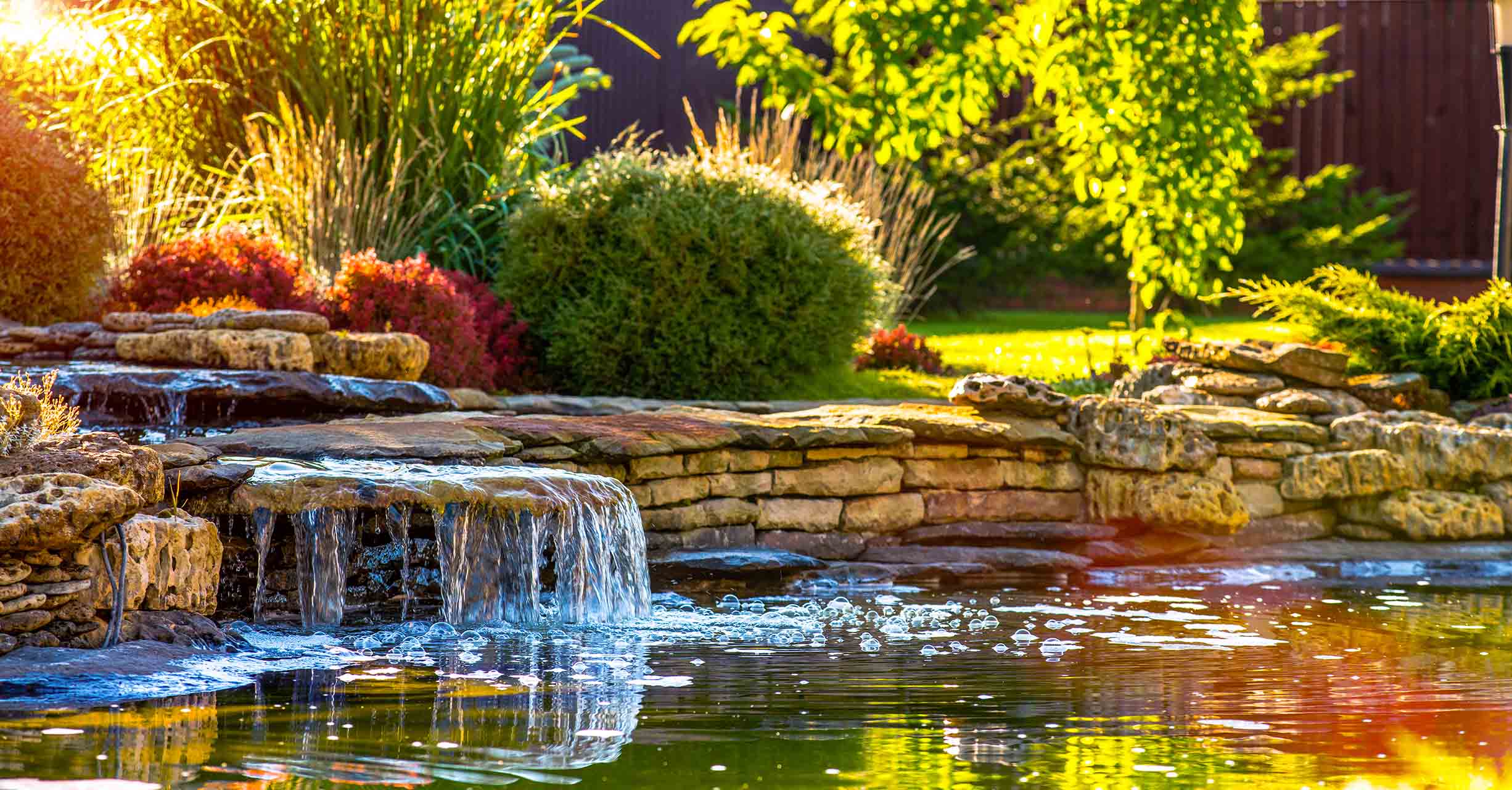 Wunderschön gestalteter Garten mit Blumenbeeten und einem Teich, Darstellung von Gartenpflege und Landschaftsgestaltung
