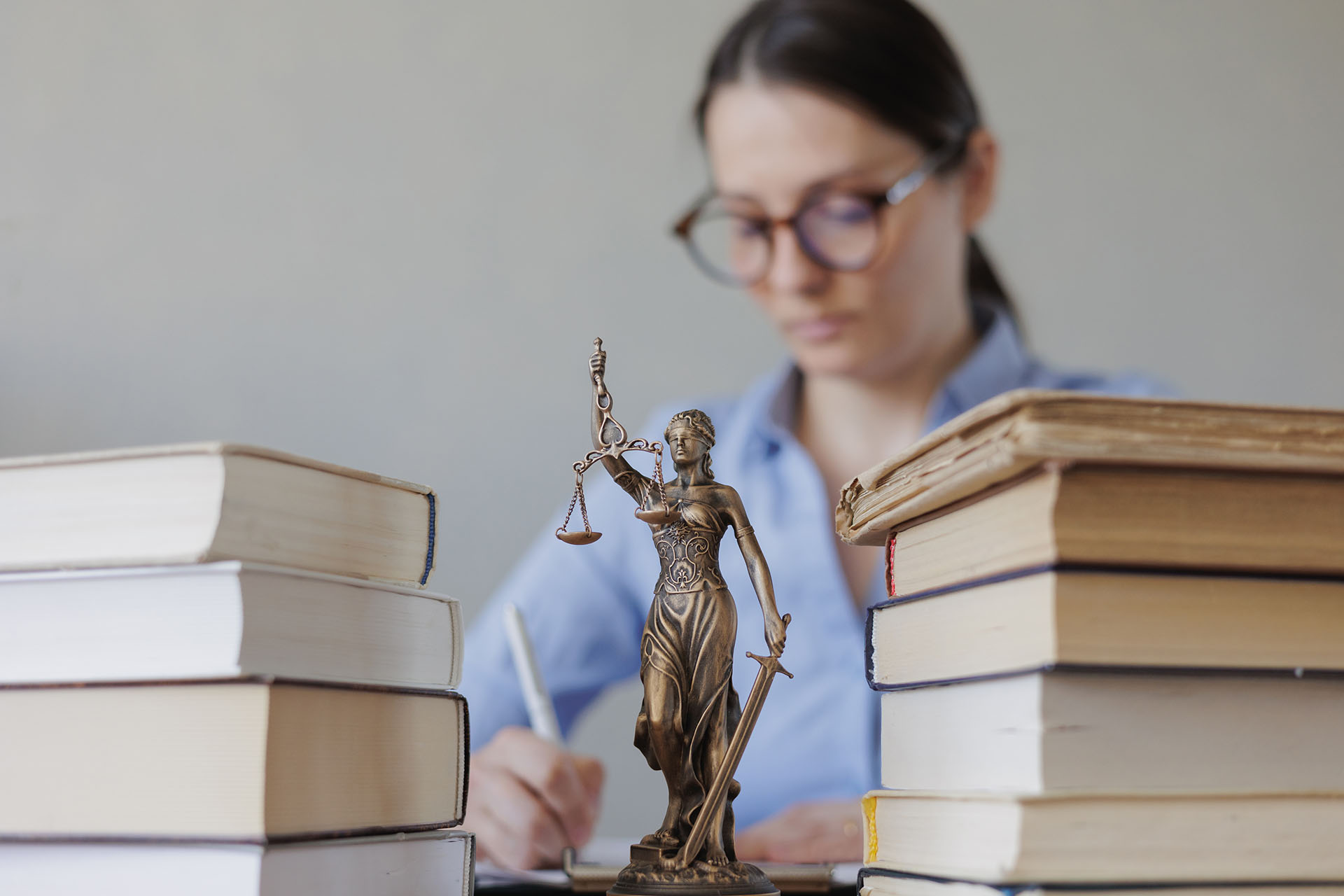 Rechtsanwältin am Schreibtisch, auf dem juristische Fachbücher und Gesetzestexte liegen