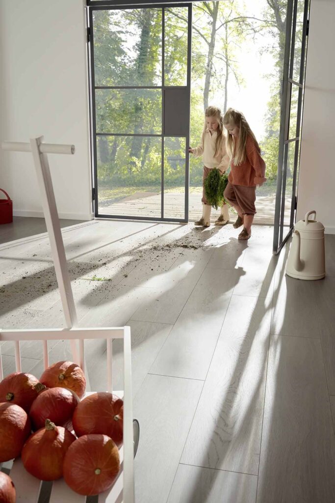 Zwei Kinder kommen mit schmutzigen Schuhen ins Haus, der Bioboden bleibt leicht zu reinigen.