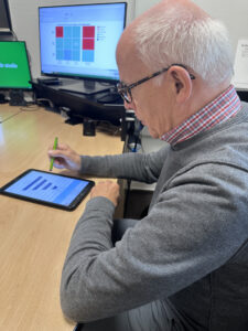 Hörtest Bremen mit der Revolout-Methode: Ein älterer Mann gibt am Tablet Daten zu seiner Hörwahrnehmung ein