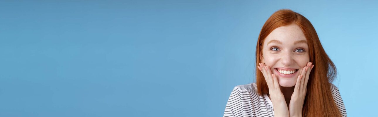 Junge Frau legt lachend die Hända an ihr Kinn